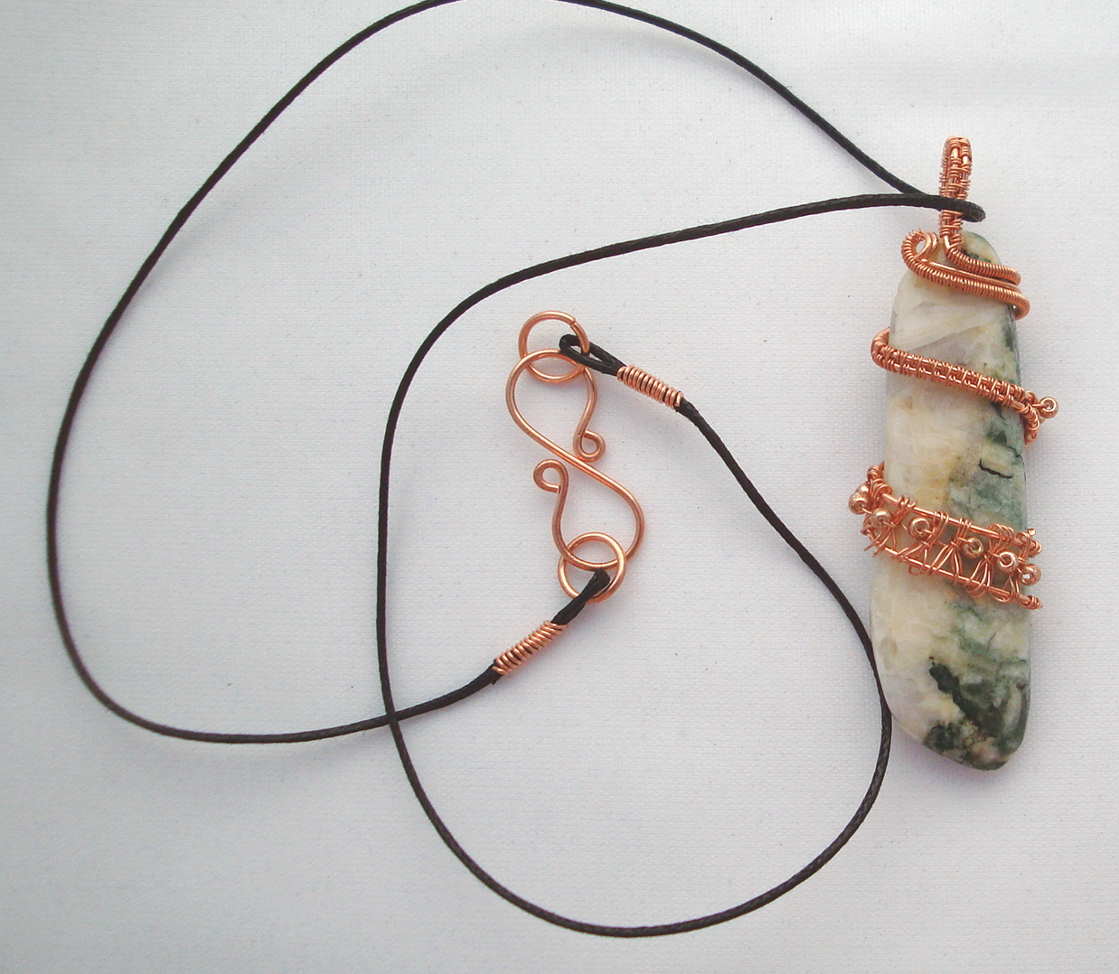 White and green stone wrapped with copper wire