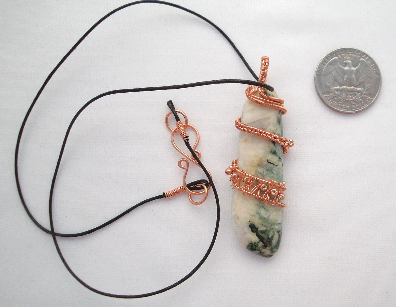 White and green stone wrapped with copper wire
