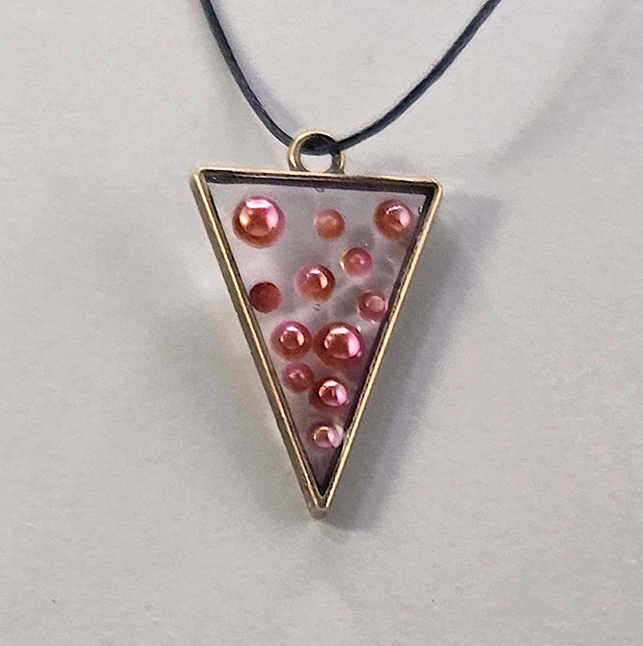 Resin pendant using bronze open bezel with pearl inclusions.