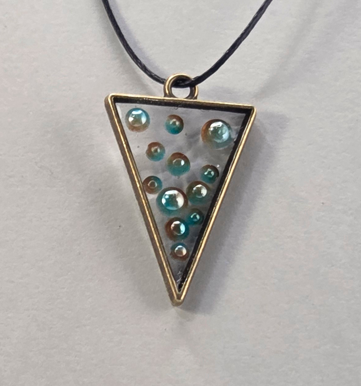Resin pendant using bronze open bezel with pearl inclusions.