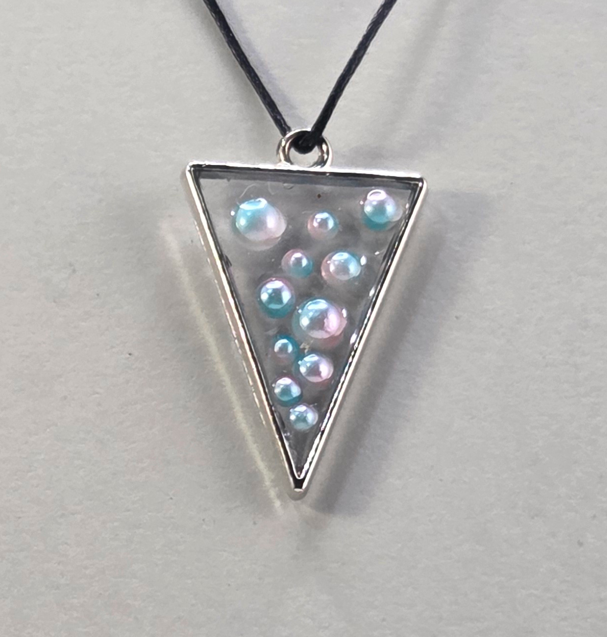 Resin pendant using bronze open bezel with pearl inclusions.