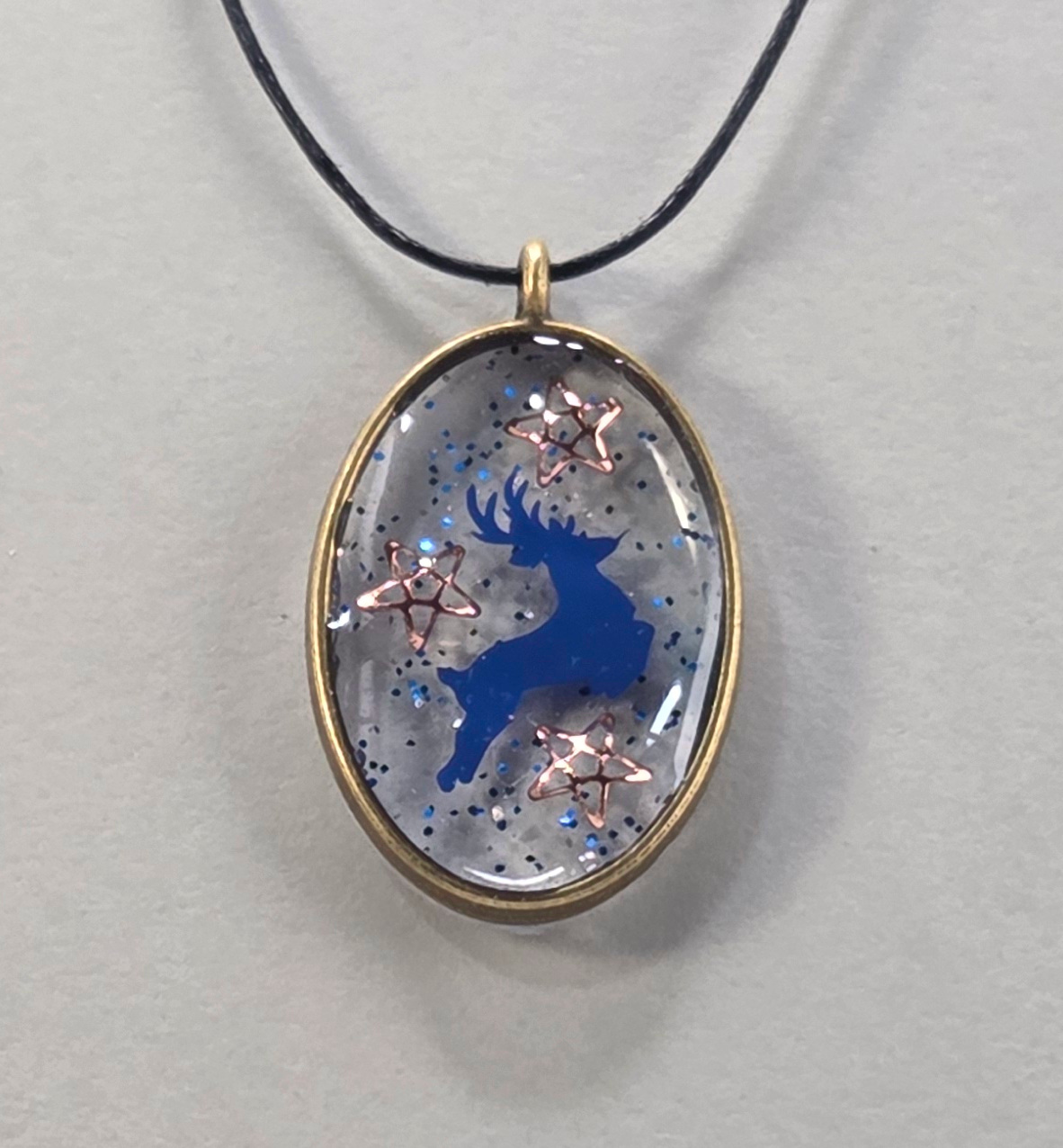Resin pendants using antique bronze open bezels and blue figures.