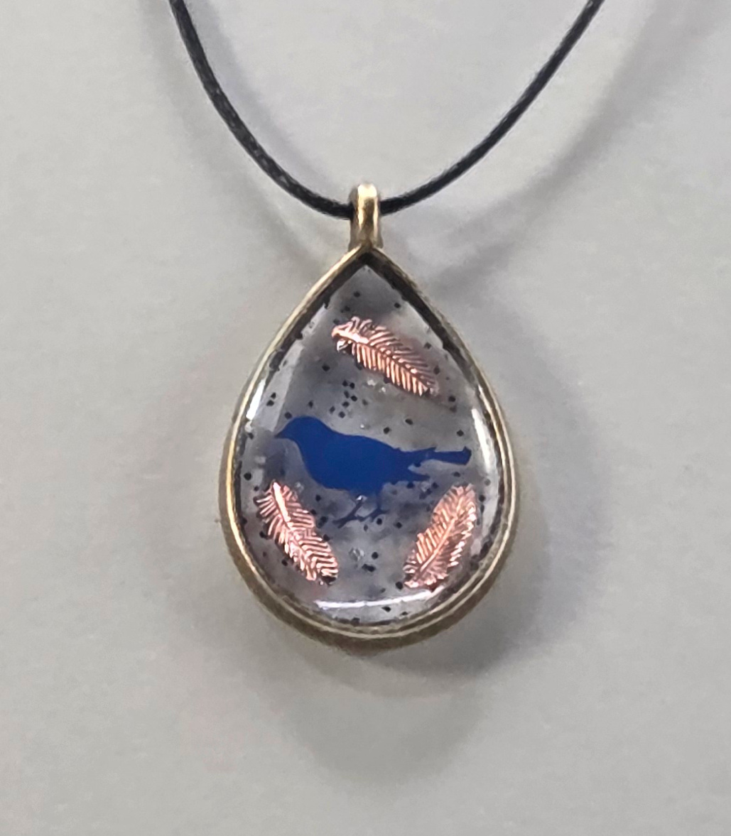 Resin pendants using antique bronze open bezels and blue figures.