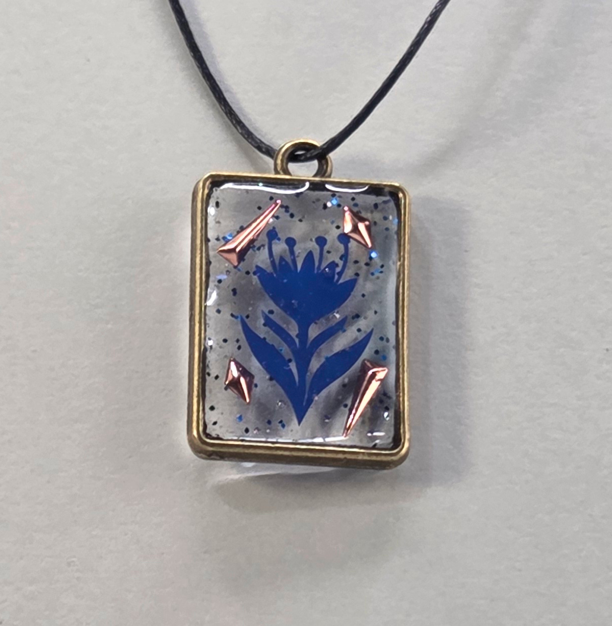 Resin pendants using antique bronze open bezels and blue figures.