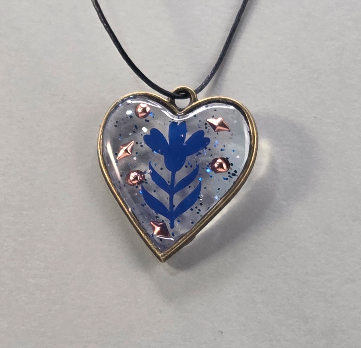 Resin pendants using antique bronze open bezels and blue figures.