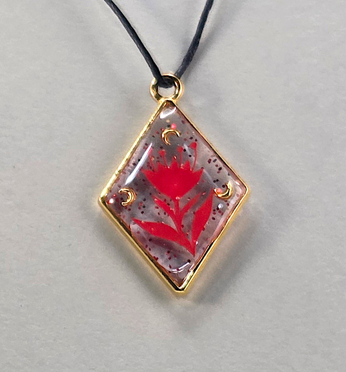 Resin pendants using bronze open bezels and red figures.