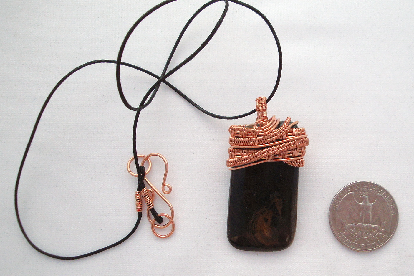 Black stone with brown swirls wrapped with copper wire